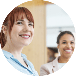 Circle photo of 2 women listening and smiling in a meeting