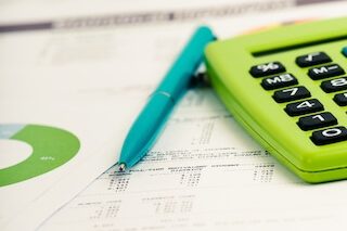 Close up of documents with a calculator and pen laying on top.