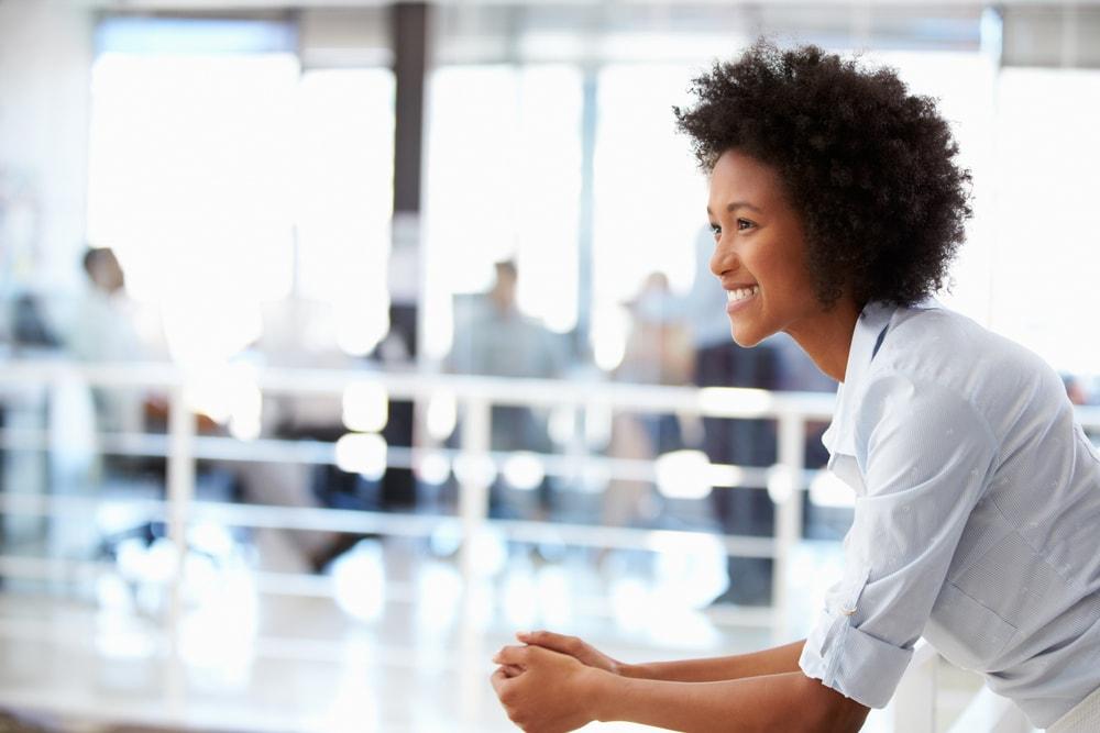 Woman smiling and leaning on a railing in a modern office