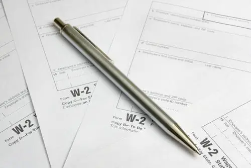 Close up of a pen lying on a lot of W-2 forms